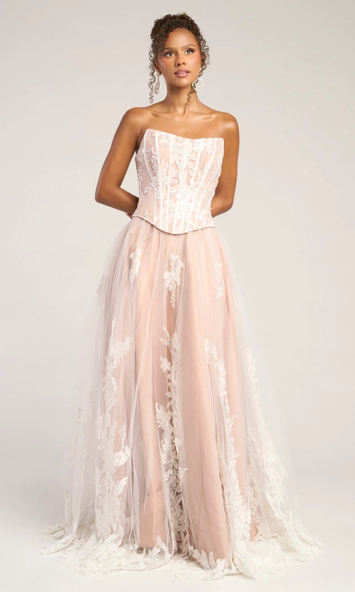 A woman stands against a plain background wearing the Portia and Scarlett PS26061 long formal dress in ivory/nude, featuring a strapless fitted bodice, A-line silhouette, and white lace floral overlay.